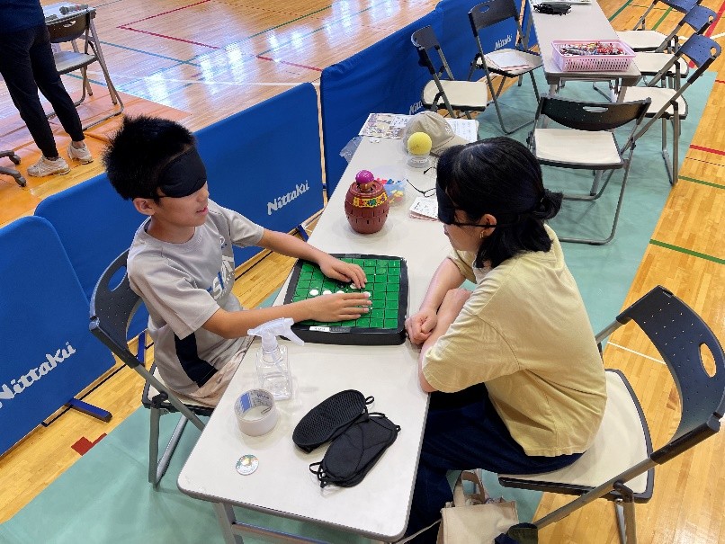 親子でアイマスクをして、マスが回転する一体オセロをしている様子。